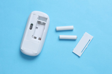 Wireless PC mouse and batteries on a blue background