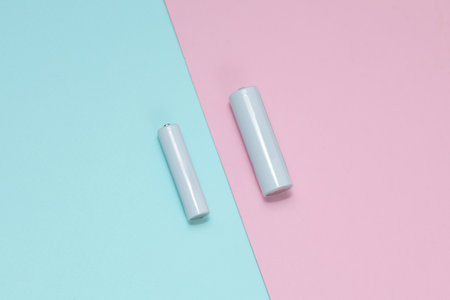 White blank aa and aaa batteries or accumulators on a blue-pink background. Mockup for designの写真素材