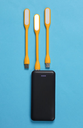Power bank with Flexible yellow USB lamps on blue background. Top view