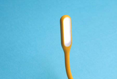 Flexible yellow USB lamp on blue background.