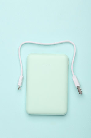 Plastic power bank with cable on blue pastel background