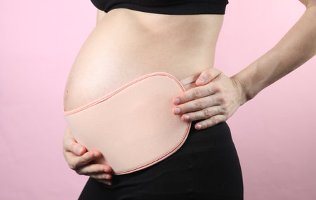 Young Pregnant woman with orthopedic belt for back and belly support. Bandage for pregnant women....