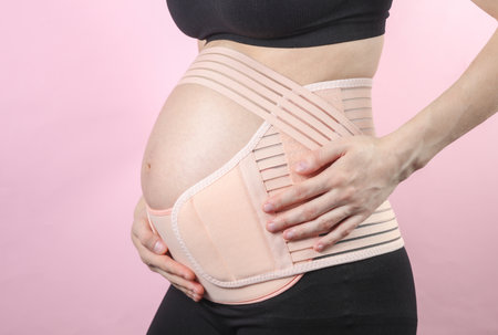 Young Pregnant woman with orthopedic belt for back and belly support. Bandage for pregnant women....