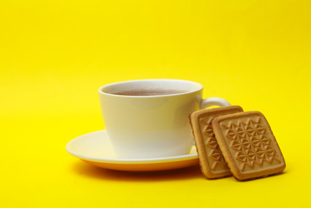 Cup of tea with cookies on a yellow background