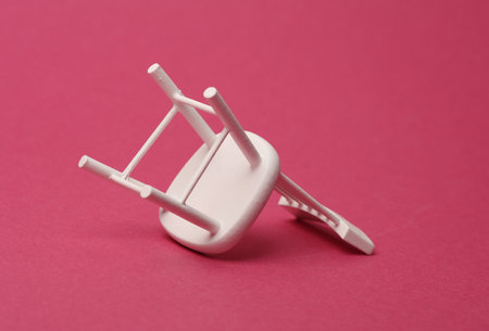 Inverted miniature chair on a pink background. Business conceptの写真素材