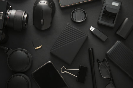 Flat lay composition of Modern black gadgets and accessories on a dark black background. Top view