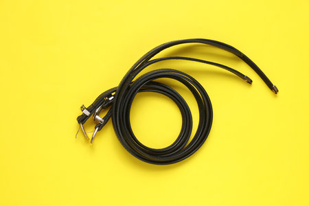 Women's black leather belts on yellow background. Fashion accessories. Flat lay. Top view