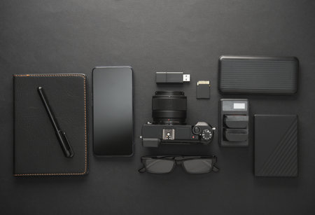 Modern equipment and accessories of a photographer on dark black background. Flat lay