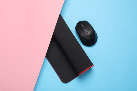 Black PC mouse with PC mouse pad on a pink blue background