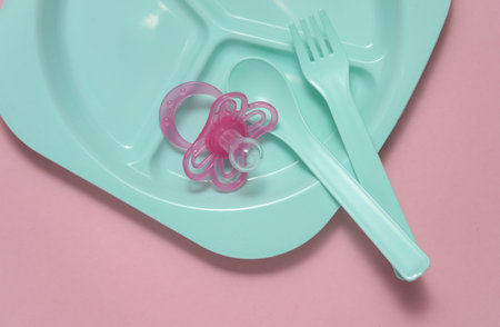 Set of plastic dishes for feeding baby on pink background. Top viewの写真素材