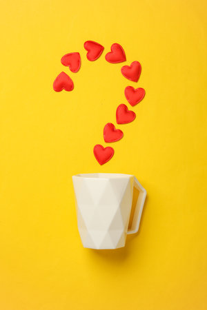 Cup with hearts in a question mark on a yellow backgroundの写真素材