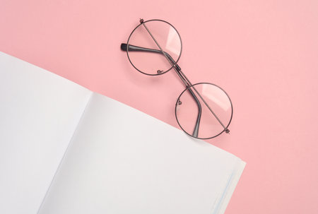 Open empty white notebook with eyeglass on a pink background. Template for designの写真素材