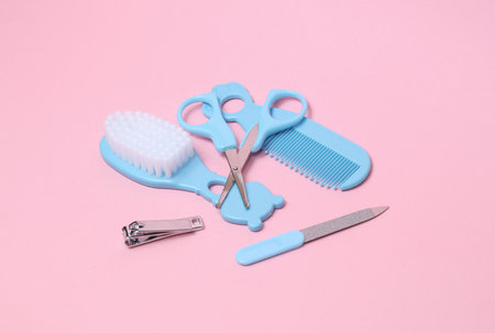 Baby care set on a pink background. Scissors, comb, nail file and tweezers.