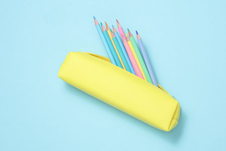 School pencil case with colored pencils on a blue background. Back to school concept