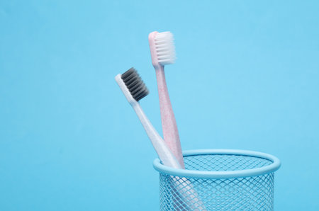 Two toothbrushes in a basket on a blue backgroundの写真素材