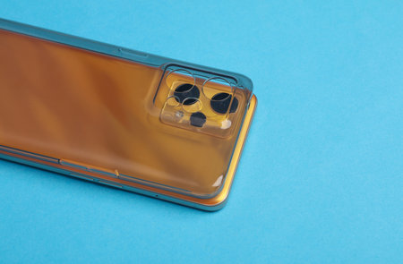 Yellow Smartphone with silicone protective case on blue backgroundの写真素材