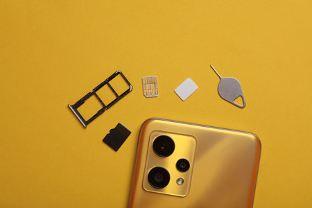 Smartphone, tray with SIM and micro SD memory cards on a yellow background. Flat lay