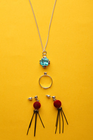 Set of jewelry on a yellow background. Pendant on a chain, ring and earrings on a yellow background. Top view. Flat layの写真素材
