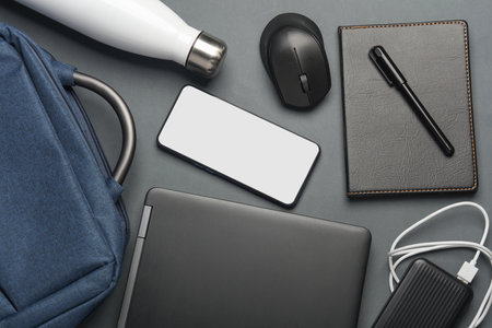 Top view of modern gray office desk table with laptop, smartphone and accessories.
