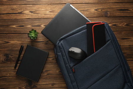 Modern gadgets For work and study. Backpack with laptop and notebook, pc mouse on wooden background....
