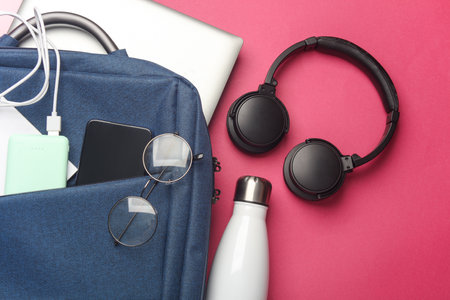 Laptop with Modern gadgets and accessories for work and study in Backpack on pink background. Top view. Flat layの写真素材