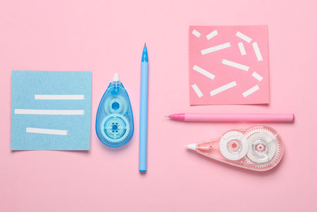 Tape correctors with memo papers and pens on pink background. Top view