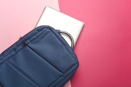Backpack with laptop on a pink background. Top view