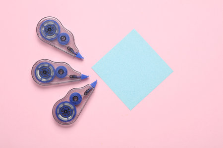 Tape correctors with memo paper on pink background. Top view