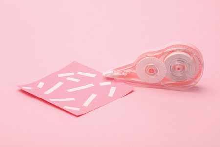 Tape corrector with memo paper on pink background.の写真素材