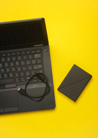 Laptop with external hard drive on yellow backgroundの写真素材