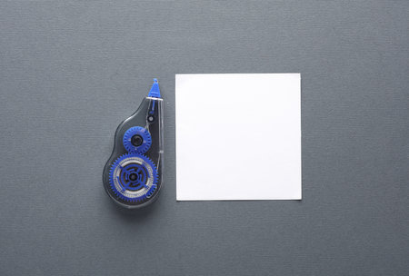 Tape corrector with memo paper on dark gray background. Top view