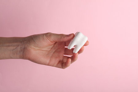 Hand holding a tooth model on pink background. Dental careの写真素材