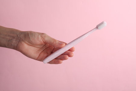 Hand holding a toothbrush on pink background. Dental careの写真素材