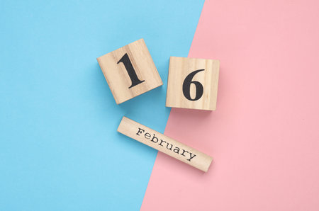Wooden block calendar with date February 16 on pink blue pastel backround. Top view. Flat layの写真素材