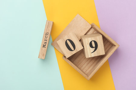Wooden block calendar with date March 09 on colored pastel backround. Top view. Flat lay