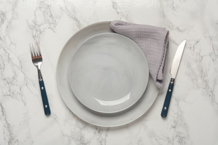 Plates, cutlery with towel on marble background. Table setting. Top view