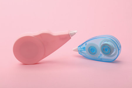 Tape correctors on pink background close up.