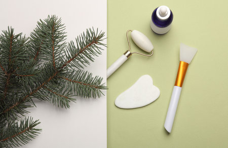 Beauty products for facial massage with a pine sprig on a green backgroundの写真素材
