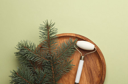 Jade facial roller with pine branch on wooden plateの写真素材