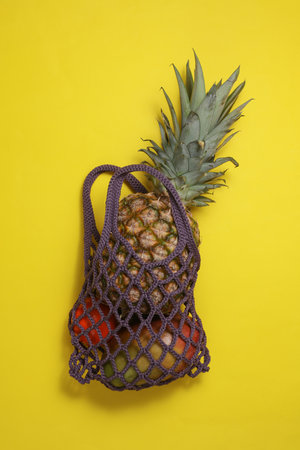 String bag with pineapple and tropical fruits on a yellow backgroundの写真素材