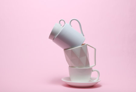Stack of different white cups on pink backgroundの写真素材