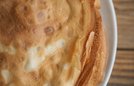 Stack of pancakes on a plate, wooden table