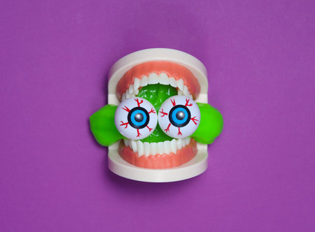 Halloween still life of jaw with eyeballs and slime on purple background