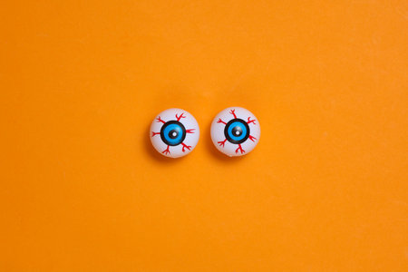 Eyeballs on orange background. Minimalistic Halloween still lifeの写真素材