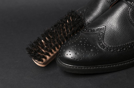 Men's black leather shoes with a brush on a black background.の写真素材