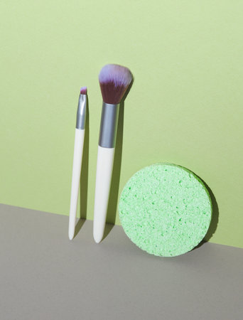 Makeup brushes and sponge on a green-gray background. Creative layoutの写真素材
