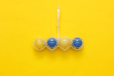 Toilet rim block cleaner on yellow background. Top view