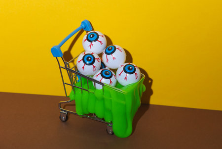 Halloween still life of shopping carts with eyeballs and slime on brown yellow backgroundの写真素材