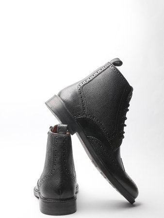 Stylish black leather men's brogue boots on a white background