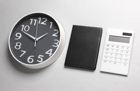 Large clock with notepad and calculator on a gray backgroundの写真素材